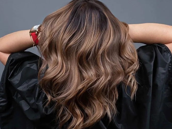 Kundin zeigt ihre frisch gewellte Balayage-Frisur von hinten